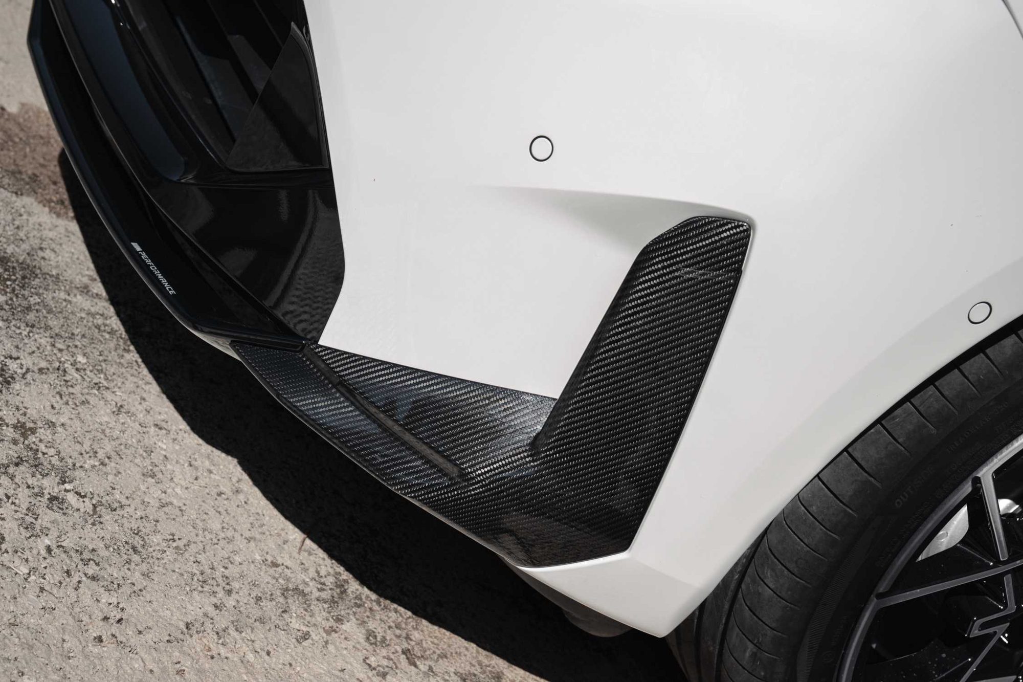 سيارة BMW i3 بيضاء من الخلف على طريق متعرج أمام سلسلة جبال ساحلية كبيرة.